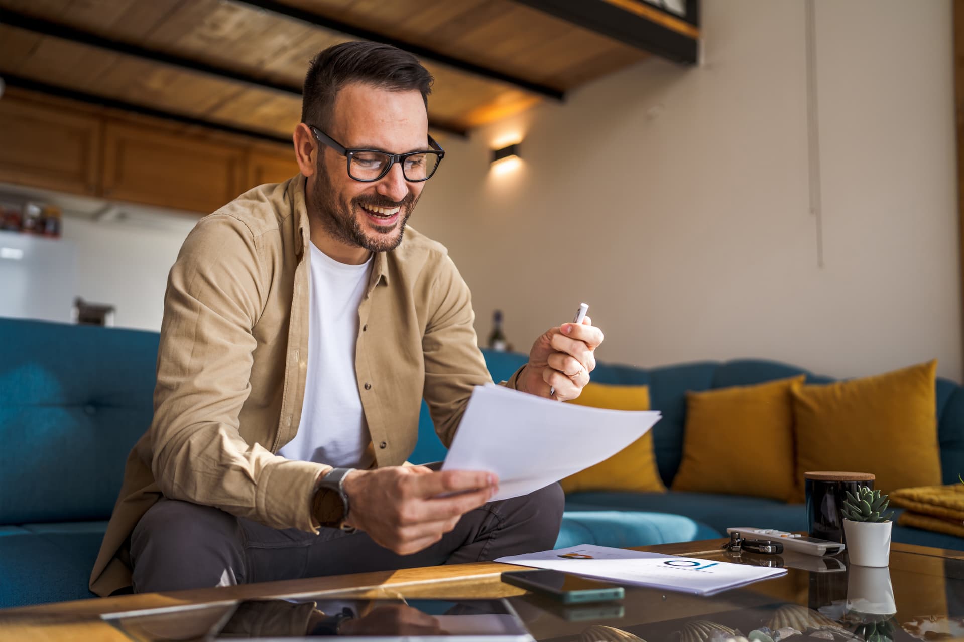 A man in smart-casual attire smiles at some paperwork