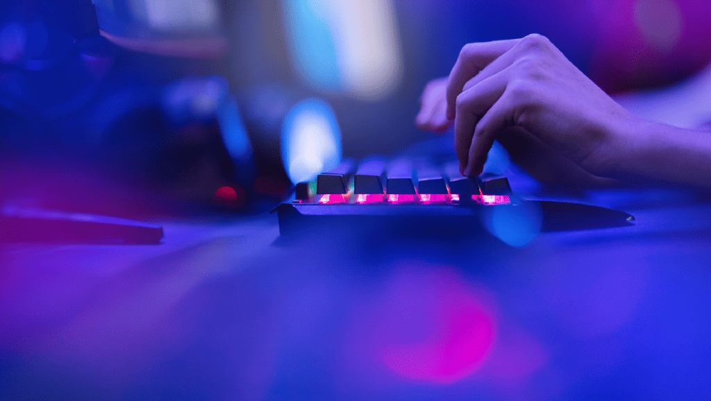 A person types on an illuminated keyboard