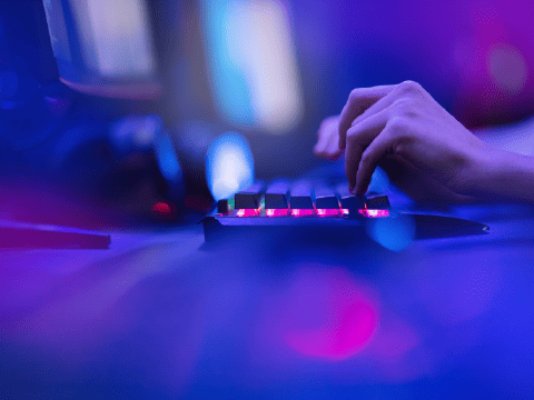 An image of somebody typing on an illuminated keyboard.