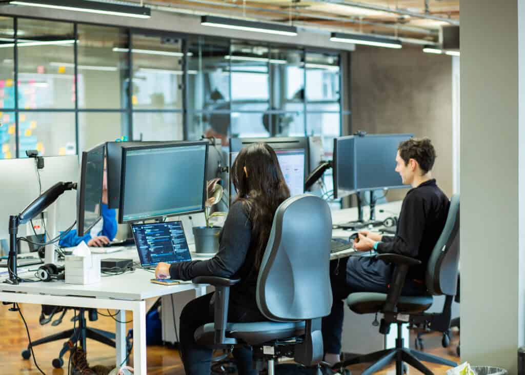 The backs of a woman and man at their desk in an office