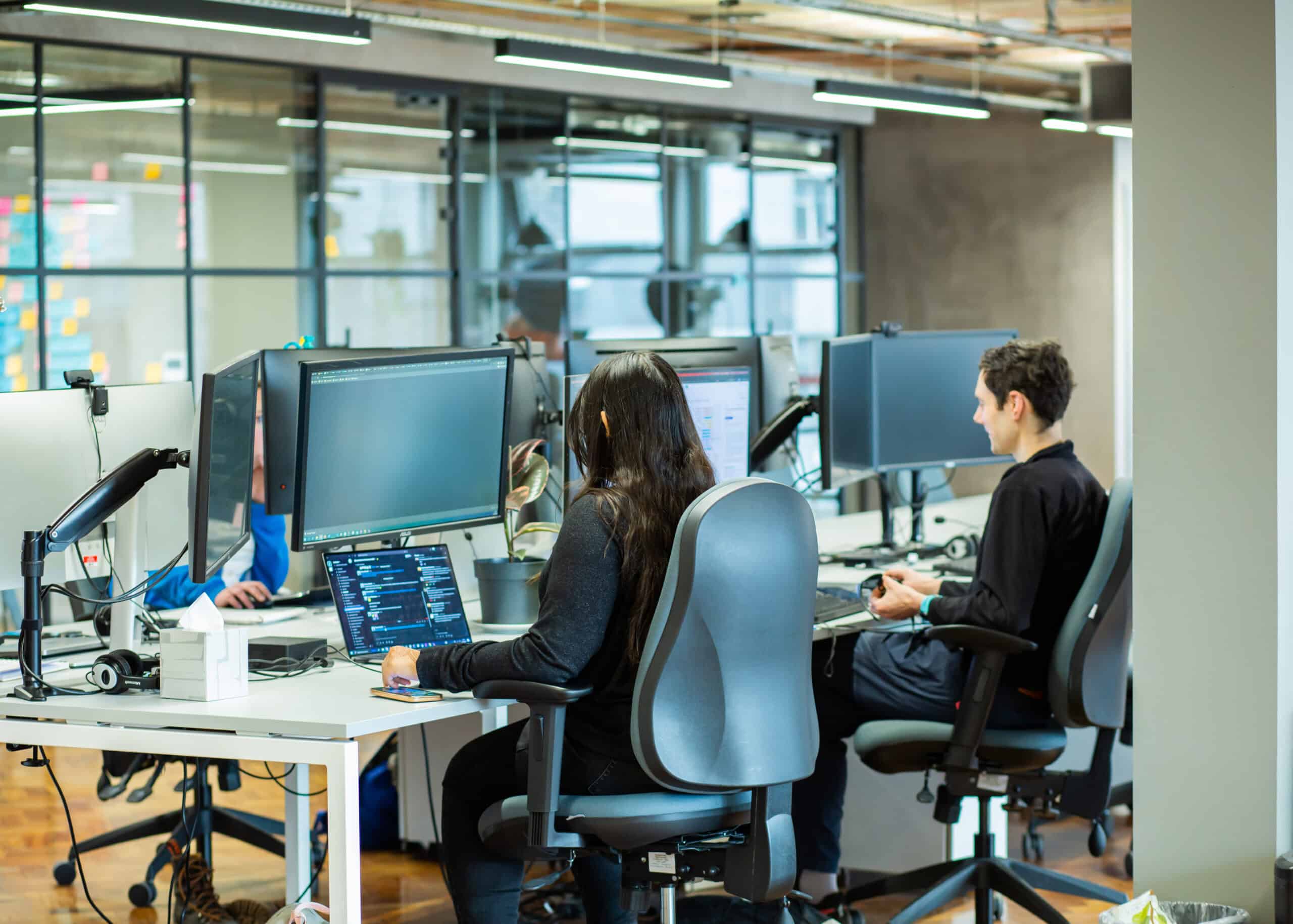 The backs of a woman and man at their desk in an office
