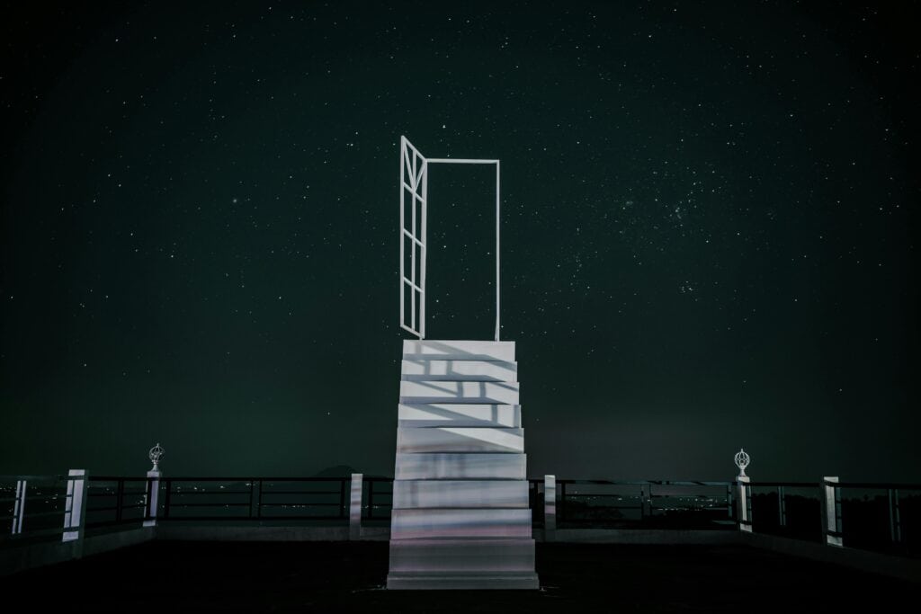 stairway-to-nightsky - Softwire An illuminated white staircase leading up to a open white door under the nightsky