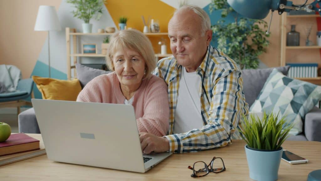 An older couple sitting together at a table using a laptop, symbolising accessibility, inclusion, and citizen interaction with digital public services.